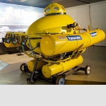 AKS 1000, Suisse 1987Un des plus petits sous-marins de deux placesL’idée du sous-marin est vieille comme le monde. En 1626 déjà, la démonstration réalisée par le sous-marin de Cornelius van Drebbel dans les eaux de la Tamise, à Londres, fit éritablement sensation. Mais il faudra attendre 1863 pour voir apparaître, en France, le premier submersible à moteur, baptisé « Plongeur ». Le concept du sous-marin ne connut toutefois définitivement le succès qu’avec l’avènement de la propulsion électrique et le soutien massif des armées du monde entier.Pour autant, l’homme n’abandonna pas son rêve d’un petit sous-marin civil pour des plongées de découverte et d’exploration. Ce rêve, August Kälin l’a réalisé avec l’AKS 1000, au bout de plus de 3’000 heures de travail de construction. La capsule pressurisée en plastique renforcé à la fibre de verre, les hublots, le trou d’homme, les flotteurs, le système de ballast et les lampes en particulier sont de sa conception. Le submersible a été principalement utilisé pour des tournages. Il s’agit probablement de l’un des plus petits sous-marins de deux places connus.